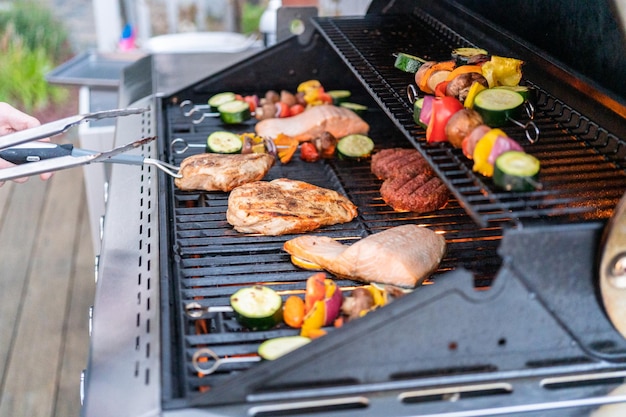 Grilling an Atlantic salmon, chicken breast, vegetable skewers, and vegetarian burgers on an outdoor grill.