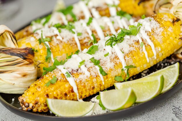 Grilling mexican street corn elote garnished with spices and fresh cilantro on a serving plate.