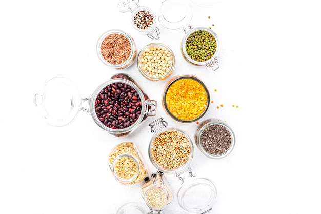 Grocery home stocks in plastic free storage and jars Various beans grains cereals legumes seeds in reusable cans White table Zero waste and sustainable llifestyle