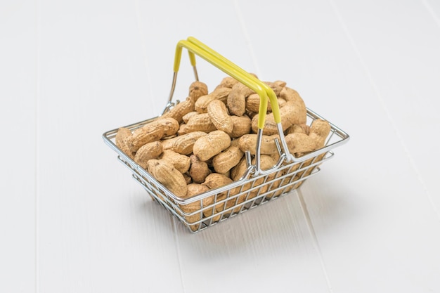 Grocery iron basket with peanuts on a white table