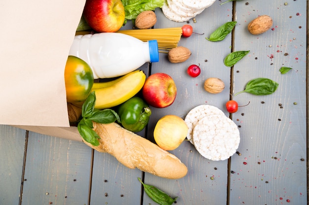 Grocery shopping concept. Different food in paper bag on wooden .  Flat lay.