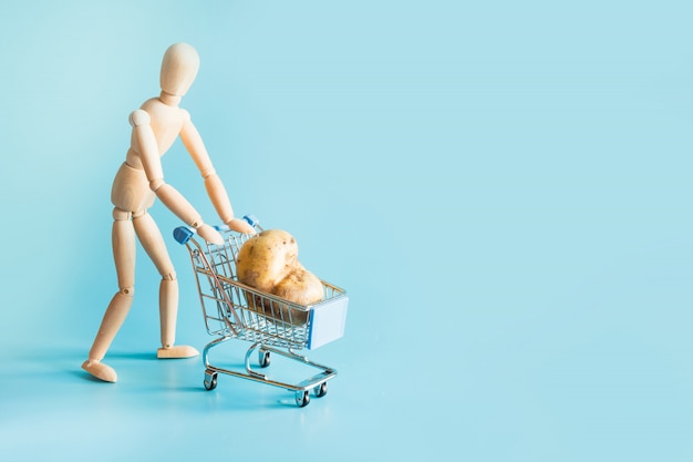 Grocery trolley with potato on blue. 