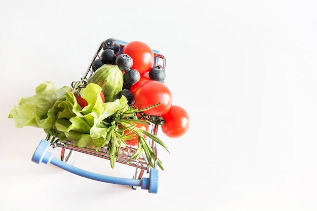 Grocery trolley with tomatoes on blue