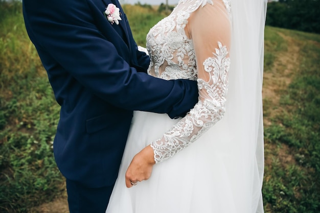 Groom and bride are hugging Happy wedding couple photo Romantic photoshoot White dress with long sleeves Lace veil