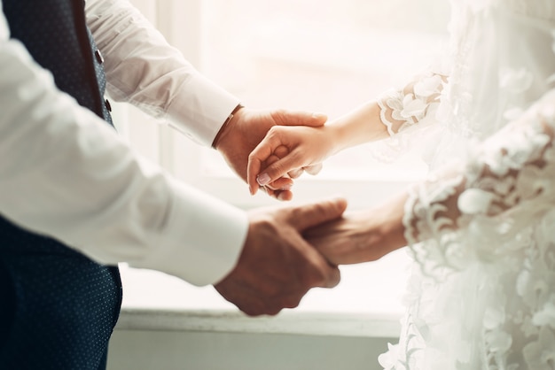 Groom and bride hold hands, close-up