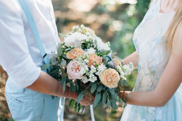 Groom and bride holding wedding bouquet together