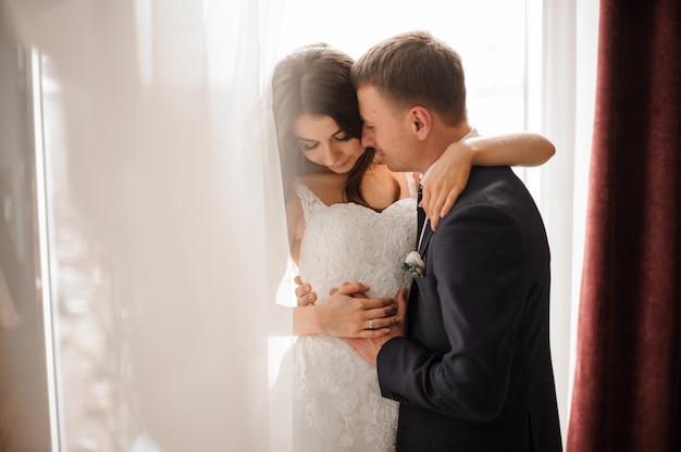 Groom and bride romantically embracing against white scene