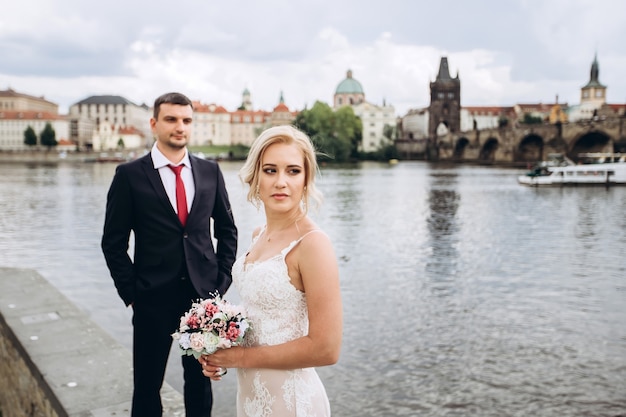 Groom and bride walk on the Charles Bridge