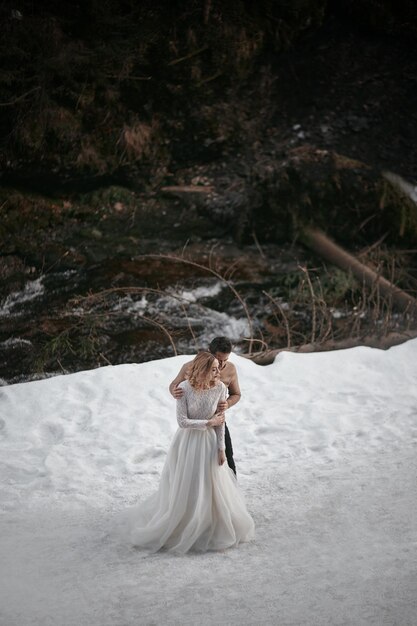 Groom and bride walking in winter forest park outdoors snowy day