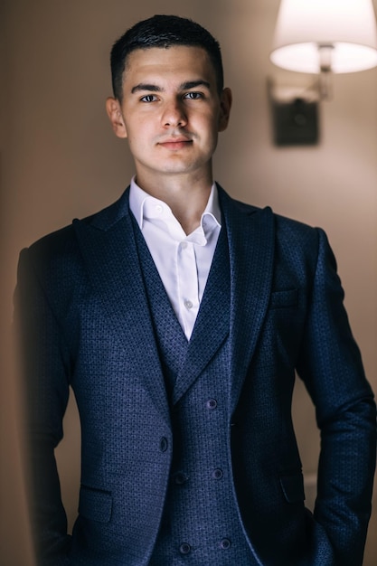 The groom in classic clothes is standing in the room Morning of the groom