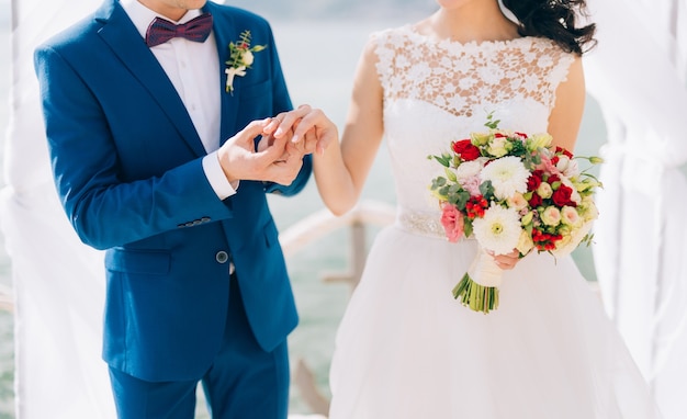 The groom dresses a ring on the finger of the bride at a wedding ceremony