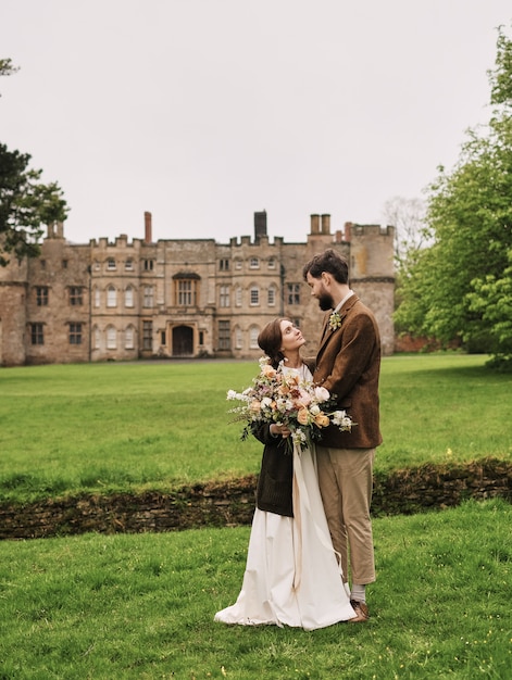 groom embracing looks at the bride on the background of a cloudy day field