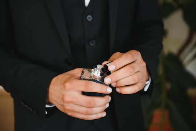 The groom on his wedding day holds two wedding rings in his hand in a hotel room The man is wearing a white shirt and blue trousers with a vest Male hand and wedding rings close up