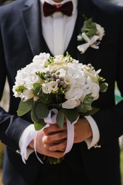 A groom holding a beautiful wedding bouquet closeup