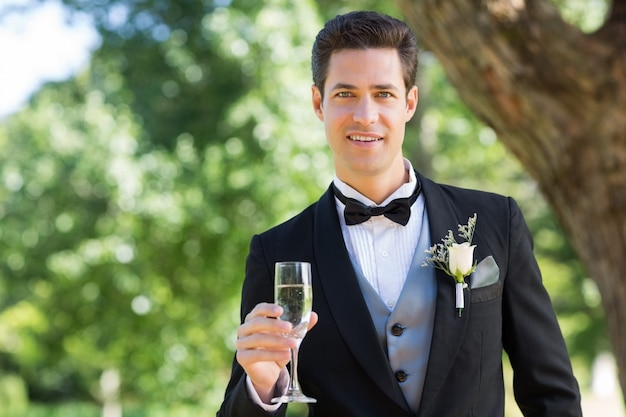 Groom holding champagne flute in garden