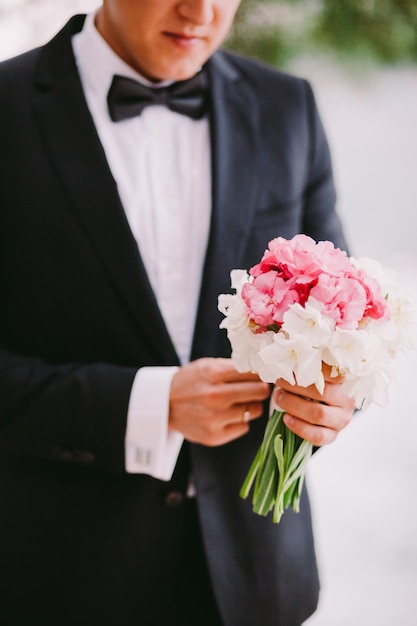 Groom holding wedding bouquet. close up shot