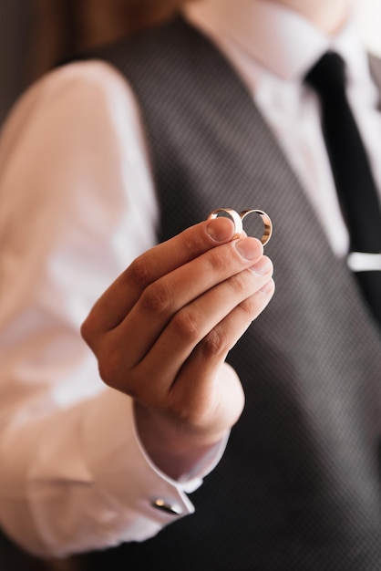 The groom holds 2 wedding rings in his hands