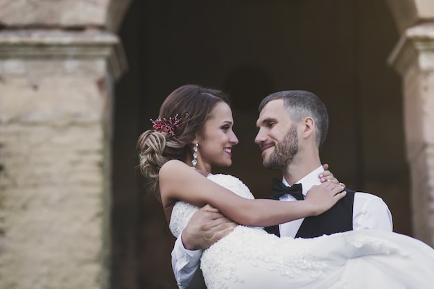 Groom holds a beautiful bride in his arms