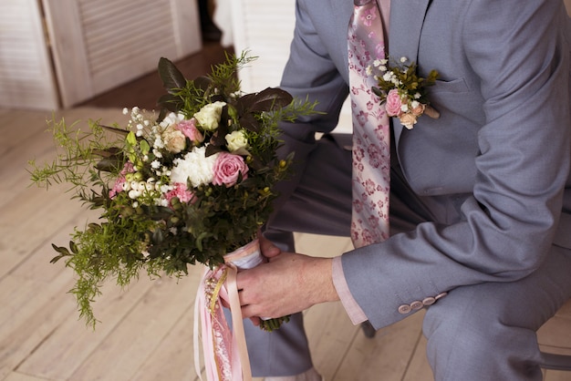 Groom holds bridal bouquet at the wedding 