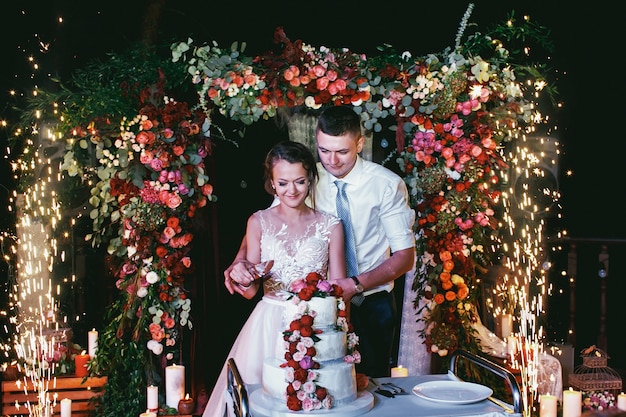 Groom hugs bride from behind while they kiss together wedding cake