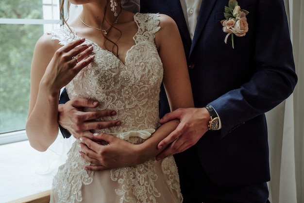 The groom hugs the bride in a wedding dress at the waist 1