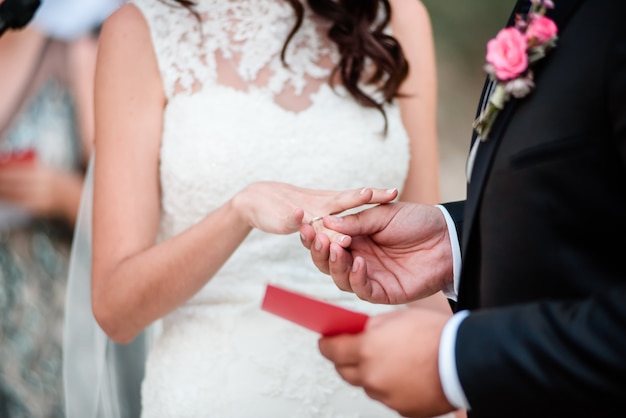 Groom is wearing a wedding ring at a wedding outdoors ceremony