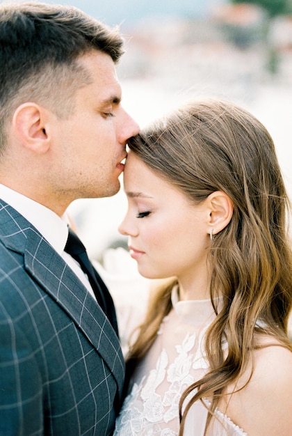 Groom kisses bride on the forehead portrait profile