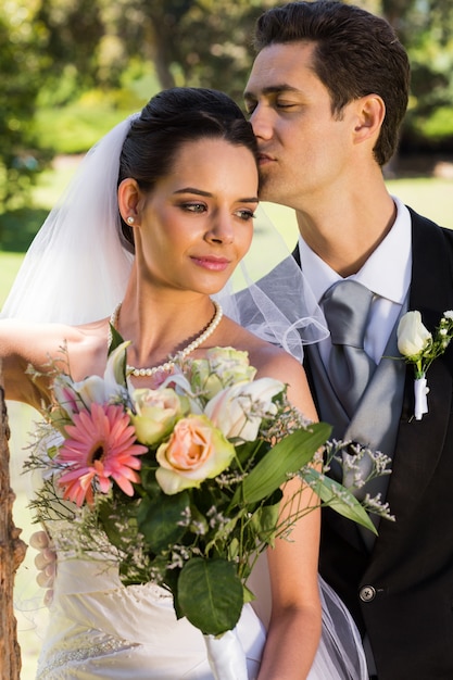 Groom kissing his beautiful bride at park