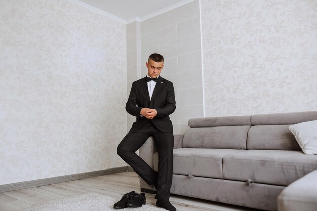 The groom prepares for the wedding ceremony in the morning in his room Grooms morning Preparation for the grooms morning The groom put on a jacket The confident look of a mature man