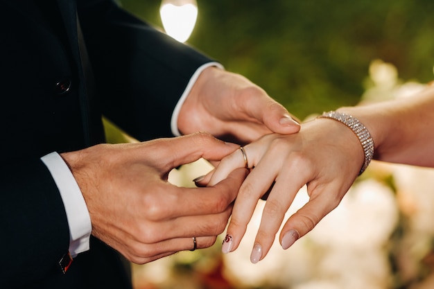 The groom puts an engagement ring on the bride's finger on their wedding day