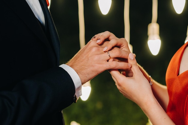 The groom puts an engagement ring on the bride's finger on their wedding day