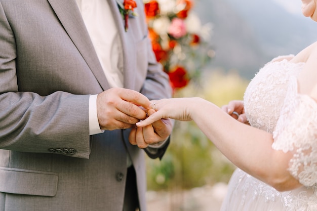 Groom puts the ring on bride hand closeup