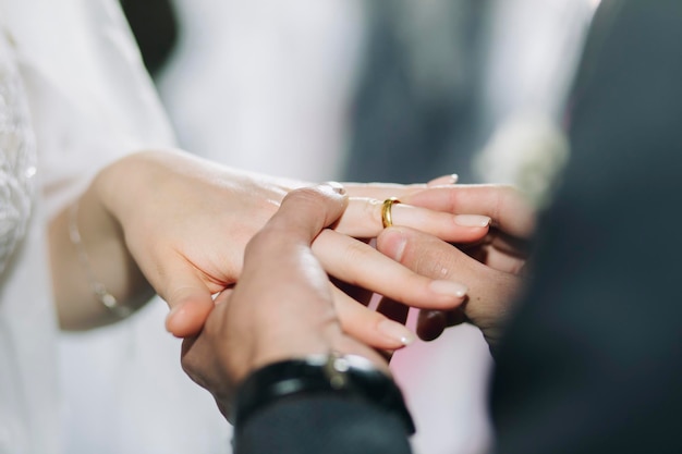 Groom puts a wedding gold ring in church during the wedding ceremony Closeup of bride and groom hands in church