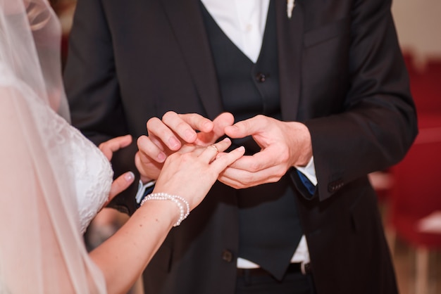 Groom putting a ring on bride's finger.