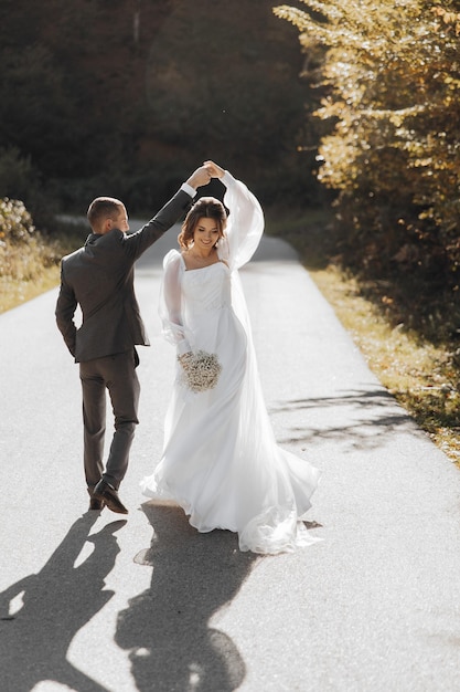 groom spins the bride under his arm happy the veil flutters in the wind Gentle and elegant couple