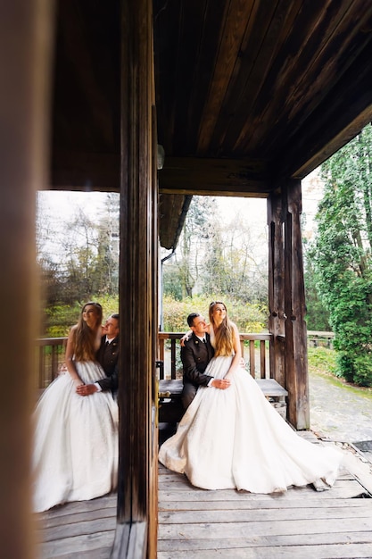 Groom in uniform and bride in wedding dress are sitting on a ben