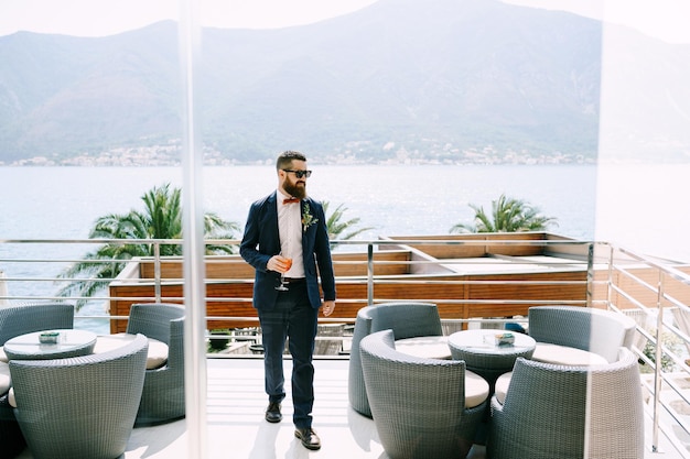 Groom walks along the hotel terrace against the backdrop of the sea and mountains