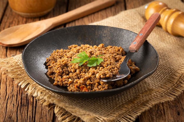 Ground beef in dark plate on the table