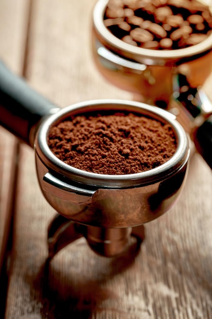 Ground coffee and beans in a holder from a coffee machine on a wooden background Coffee concept