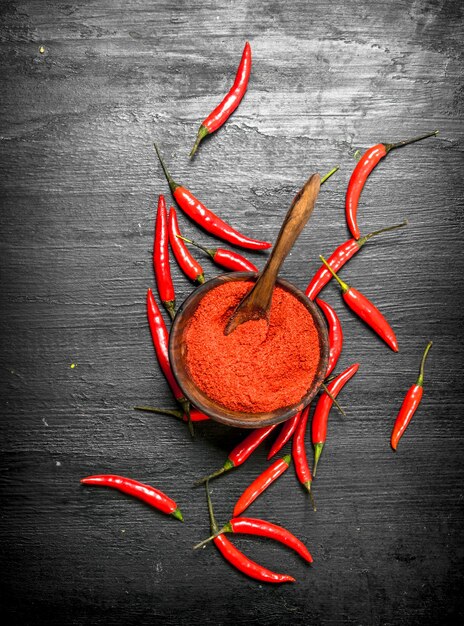 Ground hot peppers in a wooden bowl. On the black chalkboard.