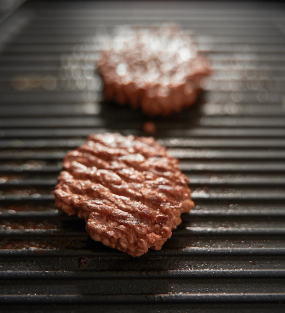 Ground meat burger patties on griddle pan cooking Dark background Grille