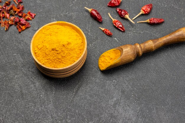 Ground turmeric in scoop and wooden bowl