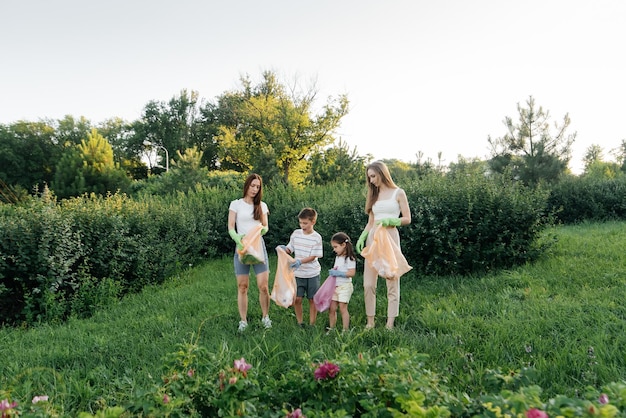 A group of adults and children together at sunset is engaged in garbage collection in the park Environmental care waste recycling Sorting garbage