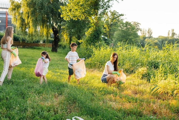 A group of adults and children together at sunset is engaged in garbage collection in the park Environmental care waste recycling Sorting garbage