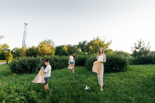 A group of adults and children together at sunset is engaged in garbage collection in the park Environmental care waste recycling Sorting garbage