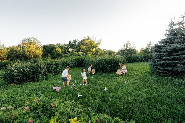 A group of adults and children together at sunset is engaged in garbage collection in the park Environmental care waste recycling Sorting garbage