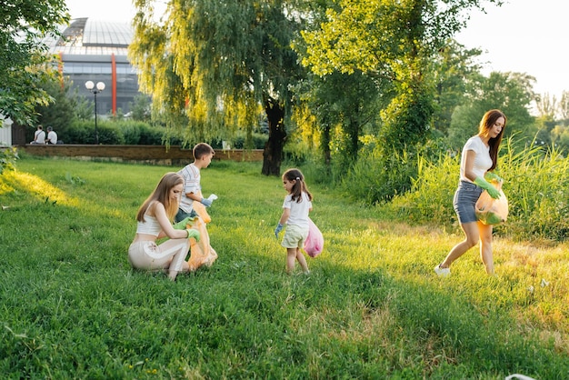 A group of adults and children together at sunset is engaged in garbage collection in the park Environmental care waste recycling Sorting garbage