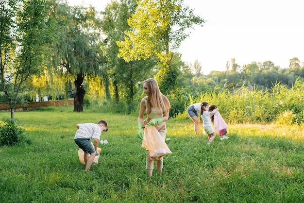 A group of adults and children together at sunset is engaged in garbage collection in the park Environmental care waste recycling Sorting garbage