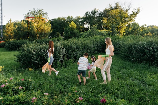 A group of adults and children together at sunset is engaged in garbage collection in the park Environmental care waste recycling Sorting garbage