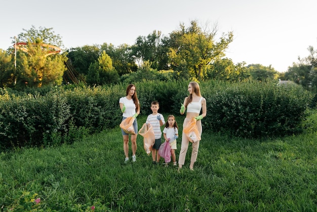 A group of adults and children together at sunset is engaged in garbage collection in the park Environmental care waste recycling Sorting garbage